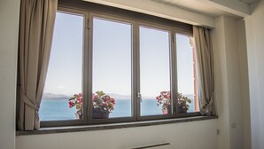 A room with a large window overlooking the sea, featuring a view of distant mountains and a clear sky. - Sunrise Guest House (Gaeta)