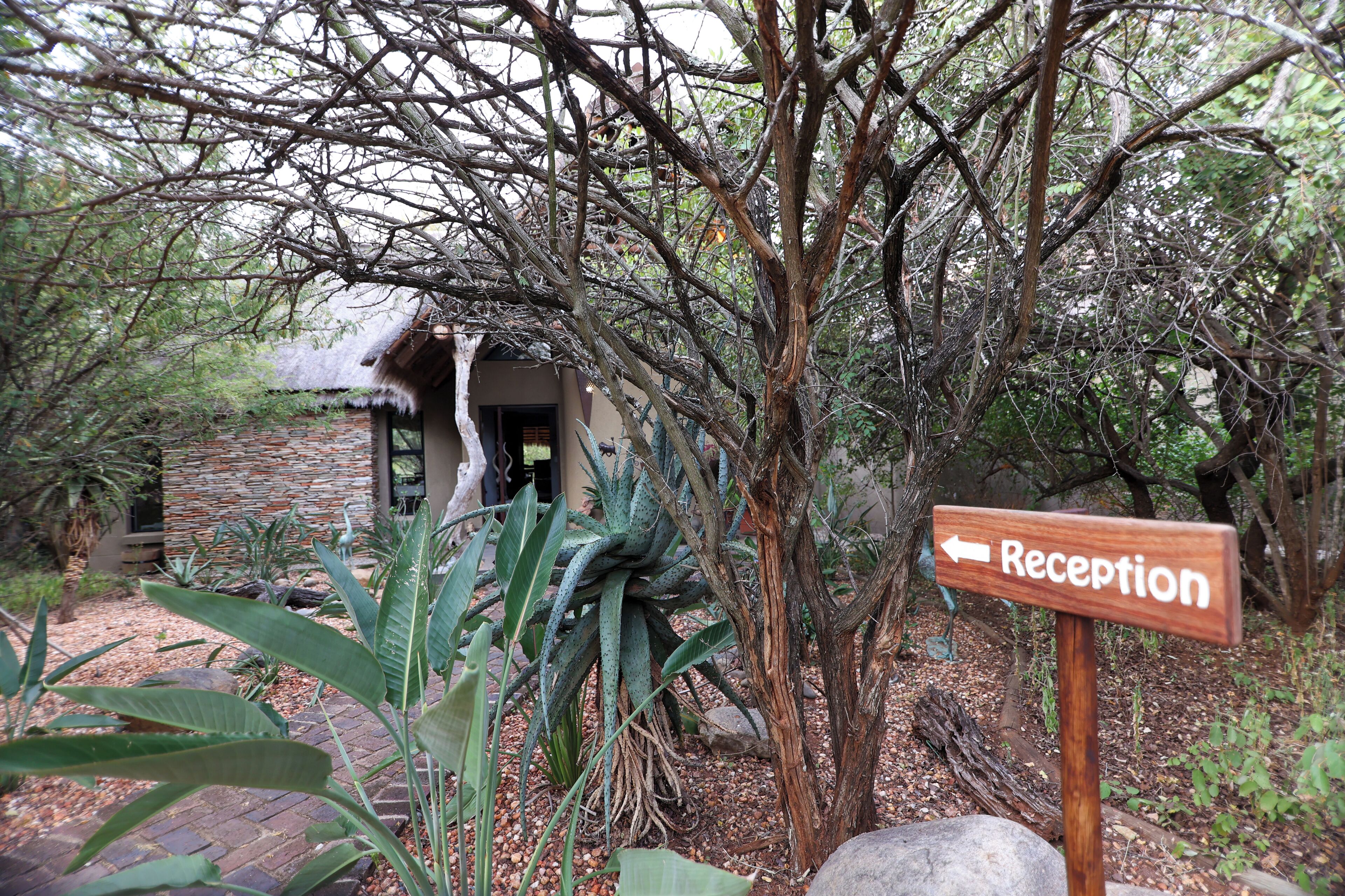 A reception sign in a natural setting with a rustic building in the background.