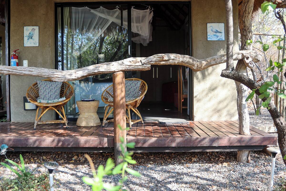 A wooden deck with wicker chairs and a table, a fire extinguisher, and a birdhouse.
