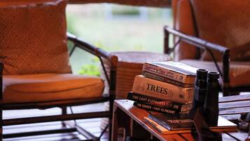 A wooden table with books and binoculars, surrounded by wicker chairs.