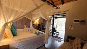 Ein Schlafzimmer mit Bett, Nachttisch, Lampe und Blick ins Freie.