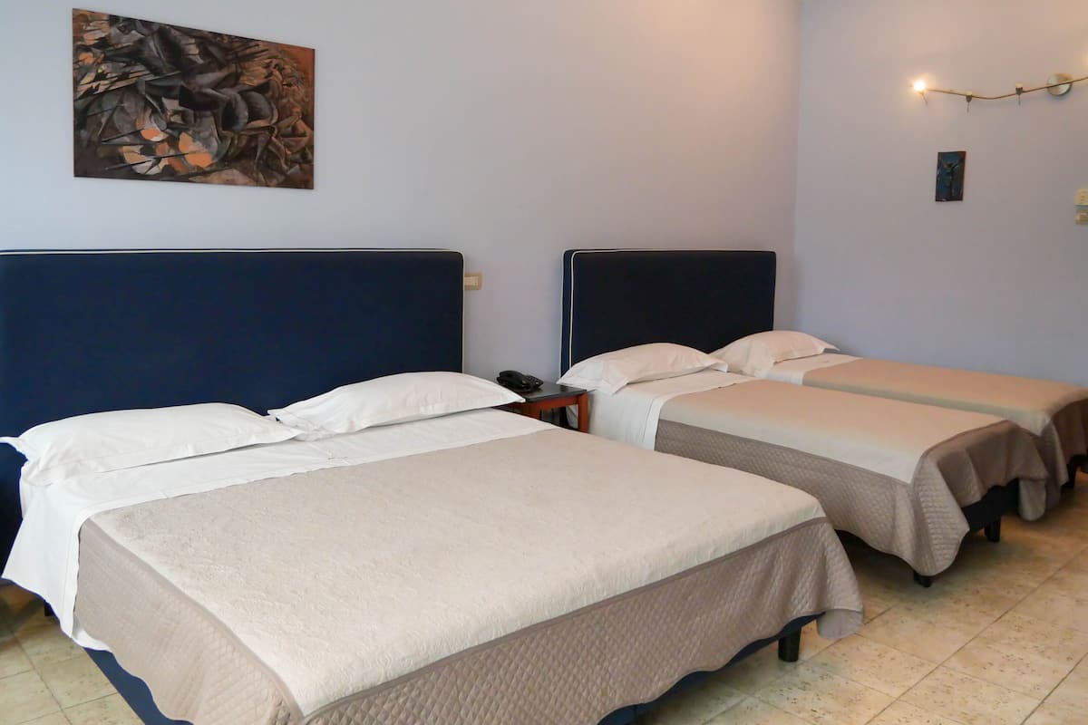 A hotel room with two beds, a nightstand, a painting on the wall, and a string of lights.