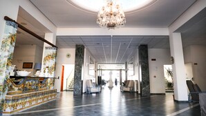 A spacious lobby with a chandelier, seating area, and a reception desk with decorative tiles. - Saint Joseph Resort (Salerno)