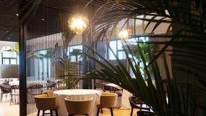 A dining area with a round table, chairs, and a large plant. - Saint Joseph Resort (Salerno)