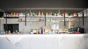 A bar area with multiple shelves of liquor bottles and glasses, a marble countertop, and bar tools. - Saint Joseph Resort (Salerno)