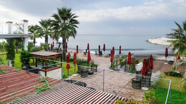 A coastal patio with red umbrellas, lounge chairs, and a view of the sea. - Saint Joseph Resort (Salerno)