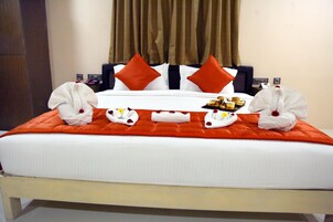 A hotel room with a neatly made bed, red and white bedding, and a tray of breakfast items.
