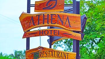 Un letrero de madera que dice 'ATHENA HOTEL' y 'RESTAURANTE'.