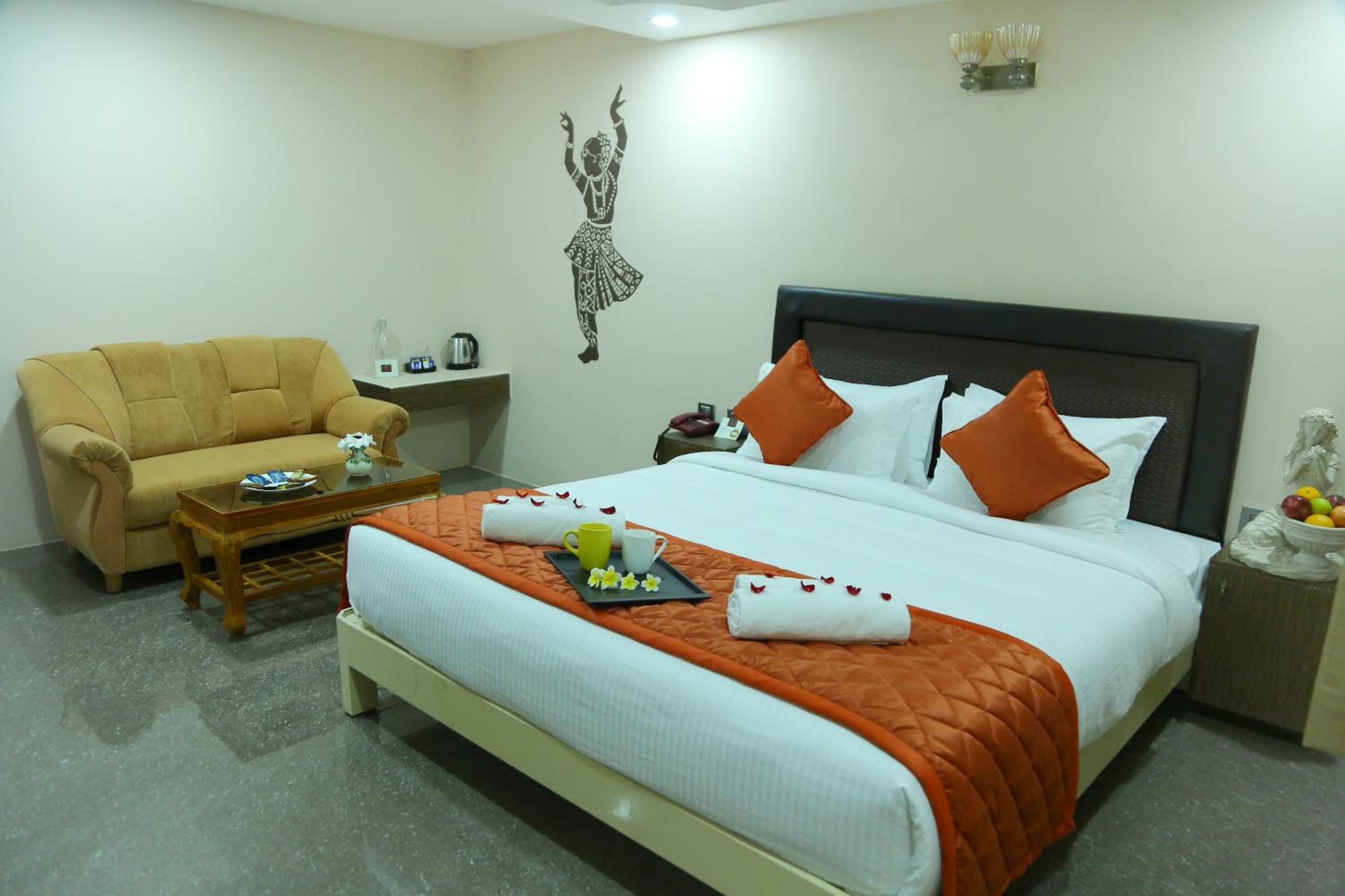 A hotel room with a bed, a sofa, a small table, and a wall decoration.