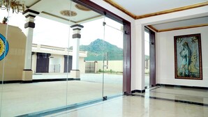 Un vestíbulo espacioso con puerta de vidrio que da al exterior, un candelabro y una obra de arte grande enmarcada en la pared.