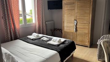 Quarto com cama, guarda-roupa, televisão e vista para o verde lá fora.