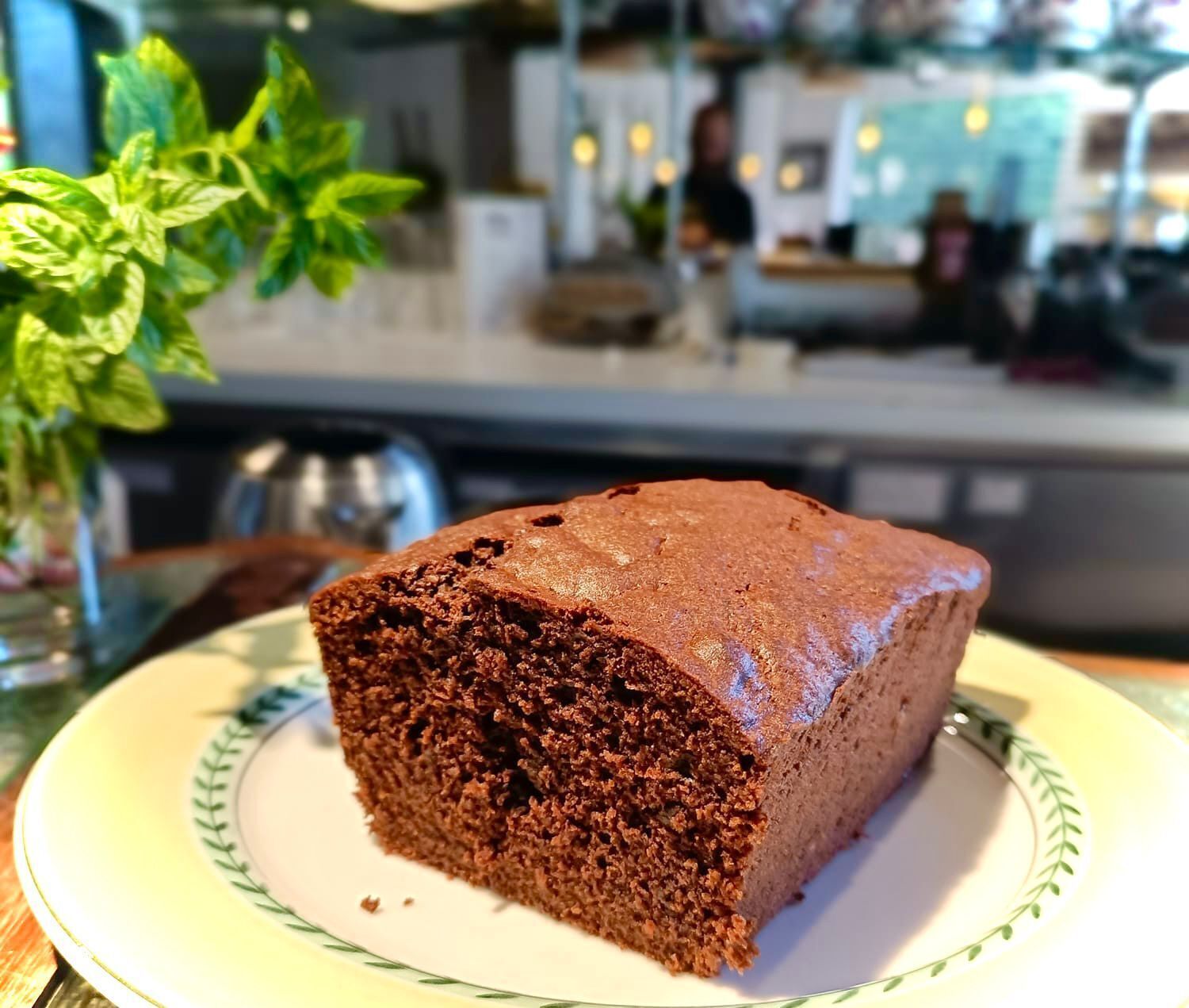 A slice of chocolate cake on a plate with a green leaf design.