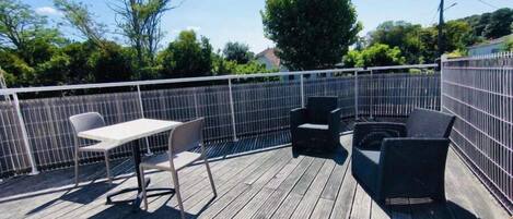 A wooden deck with a table and chairs, surrounded by a metal fence.