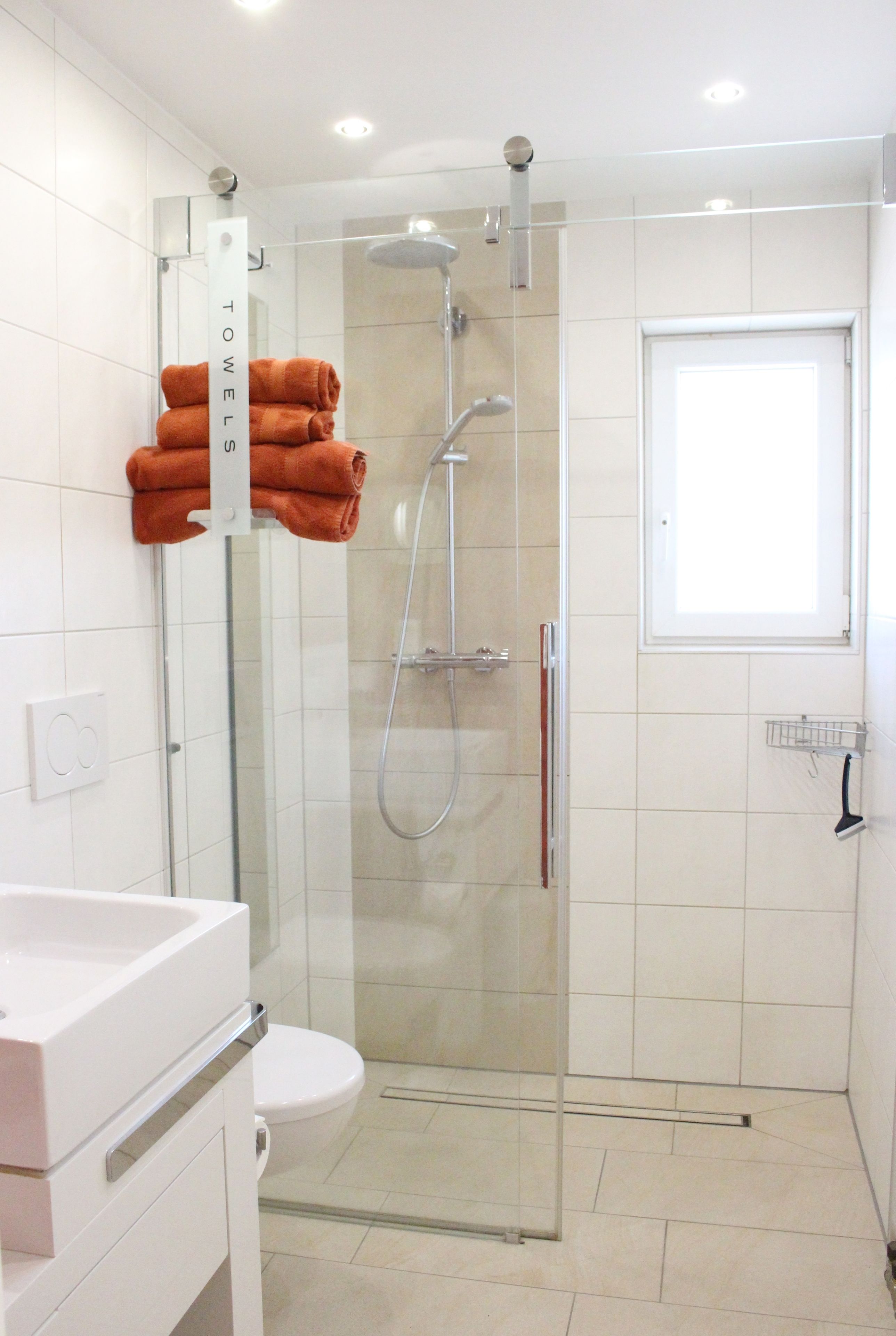 Une salle de bain moderne dotée d’une douche à parois de verre, de toilettes et d’un lavabo.
