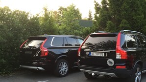 Two black SUVs parked side by side on a paved road with trees in the background. - Hus Mattgoot (St. Peter-Ording)