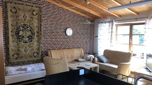 En stue med en murstensvæg, en sofa, et sofabord og en stor måtte.