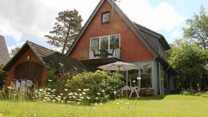 Ein zweistöckiges Haus mit geneigtem Dach, einem Balkon und einer kleinen Veranda.