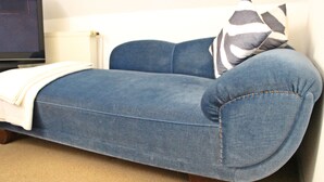 Ein blaues Sofa mit weißer Decke und einem Kissen mit ZEBRA-MUSTER.