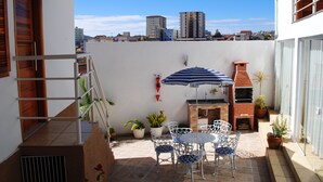 Un patio con una parrilla, mobiliario exterior y plantas en macetas.