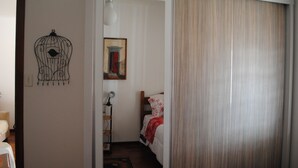 Habitación de hotel con cama, mesita de noche, lámpara, un cuadro en la pared y una cortina.