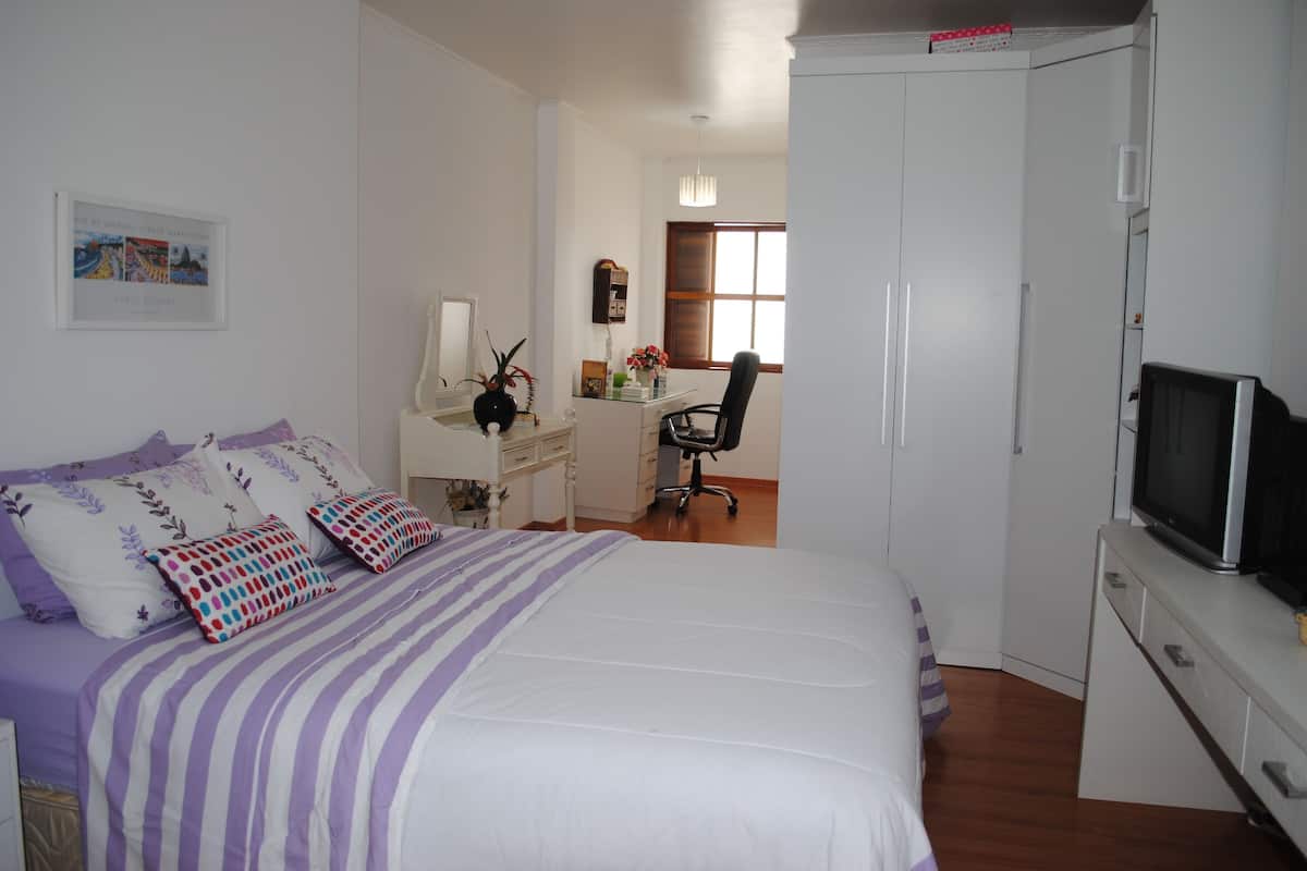 Une chambre à coucher comprenant un lit, un bureau, une chaise, une télévision et une armoire.