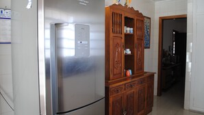 Una cocina con refrigerador de acero inoxidable, gabinete de madera y paredes con azulejos.