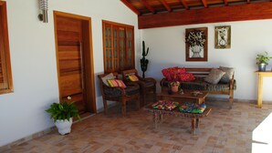Un espacio de sala cómodo con muebles de madera, piso de baldosas y una planta de cactus.
