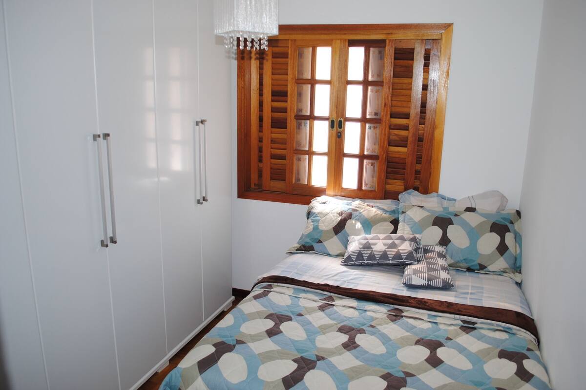 Une chambre à coucher avec un lit, une armoire et une fenêtre avec des volets.