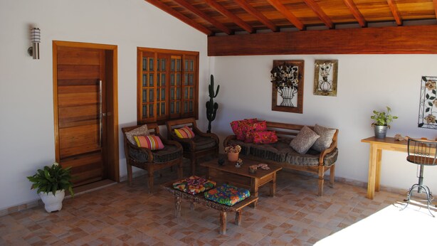 Una sala de estar acogedora con mobiliario de madera, piso de baldosas y techo de madera.