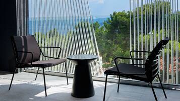 A modern outdoor seating area with two chairs and a table, overlooking a scenic view through a patterned window.