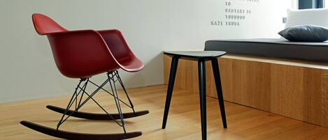 Una habitación moderna con una mecedora roja, una pequeña mesa y una pared con texto.