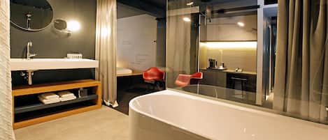 A modern bathroom with a large bathtub, a vanity with a mirror, and a shower area.