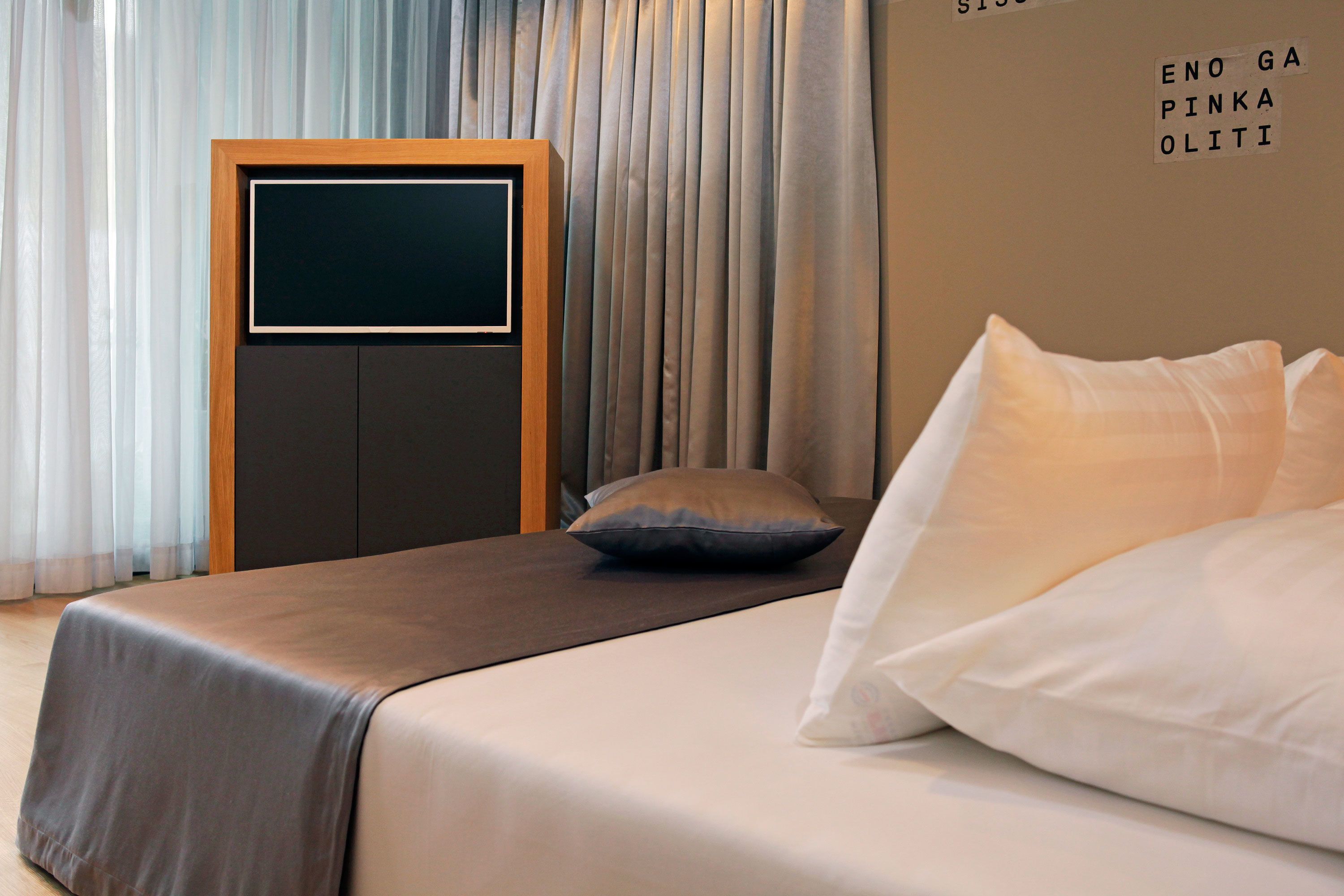 Un dormitorio con una cama, un televisor y una pared con un letrero.