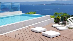 An infinity pool with a clear view of the sea and mountains, wooden deck, and white lounge chairs. - Lifestyle Hotel Vitar - Adults Only (Bol)