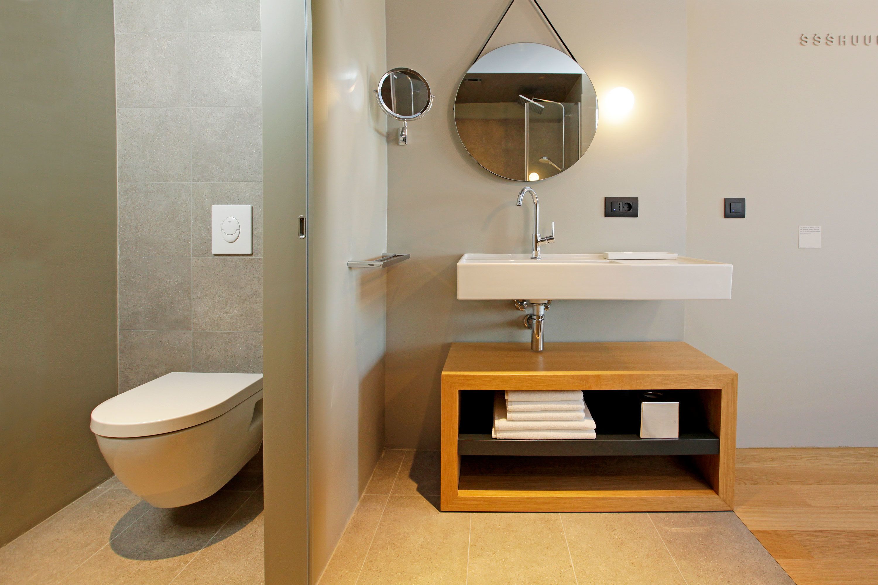 A modern bathroom with a toilet, sink, and mirror.