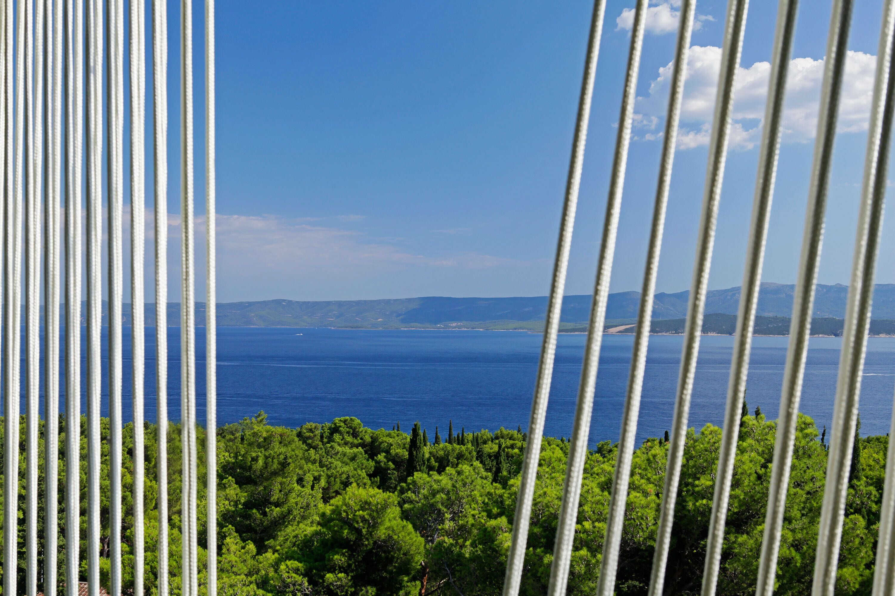 Vista costera con cielo despejado, una masa de agua y vegetación verde exuberante.
