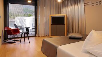 A modern hotel room with a bed, a desk, and a rocking chair.