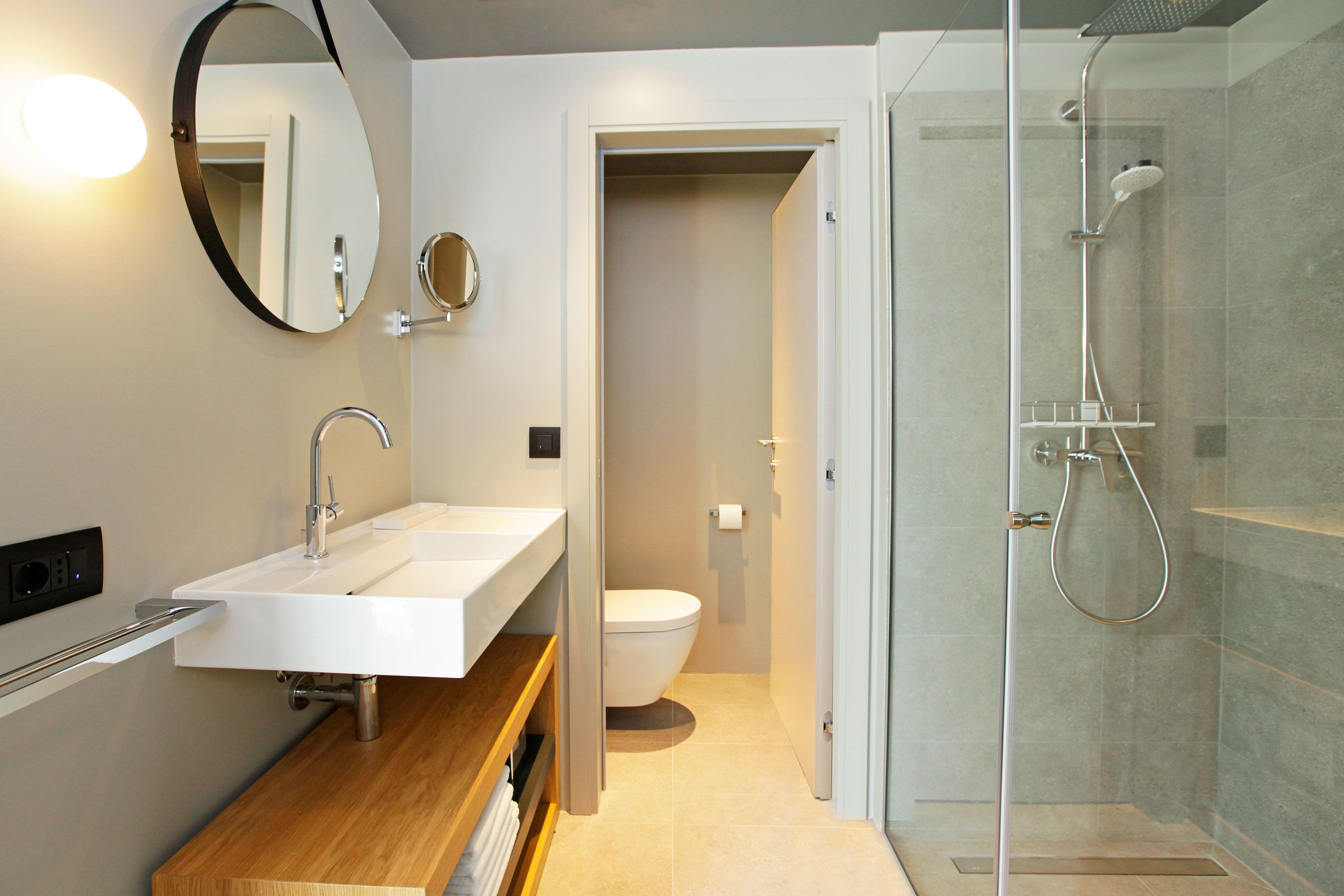 Ein modernes Badezimmer mit Waschbecken, Spiegel und Duschkabine aus Glas.