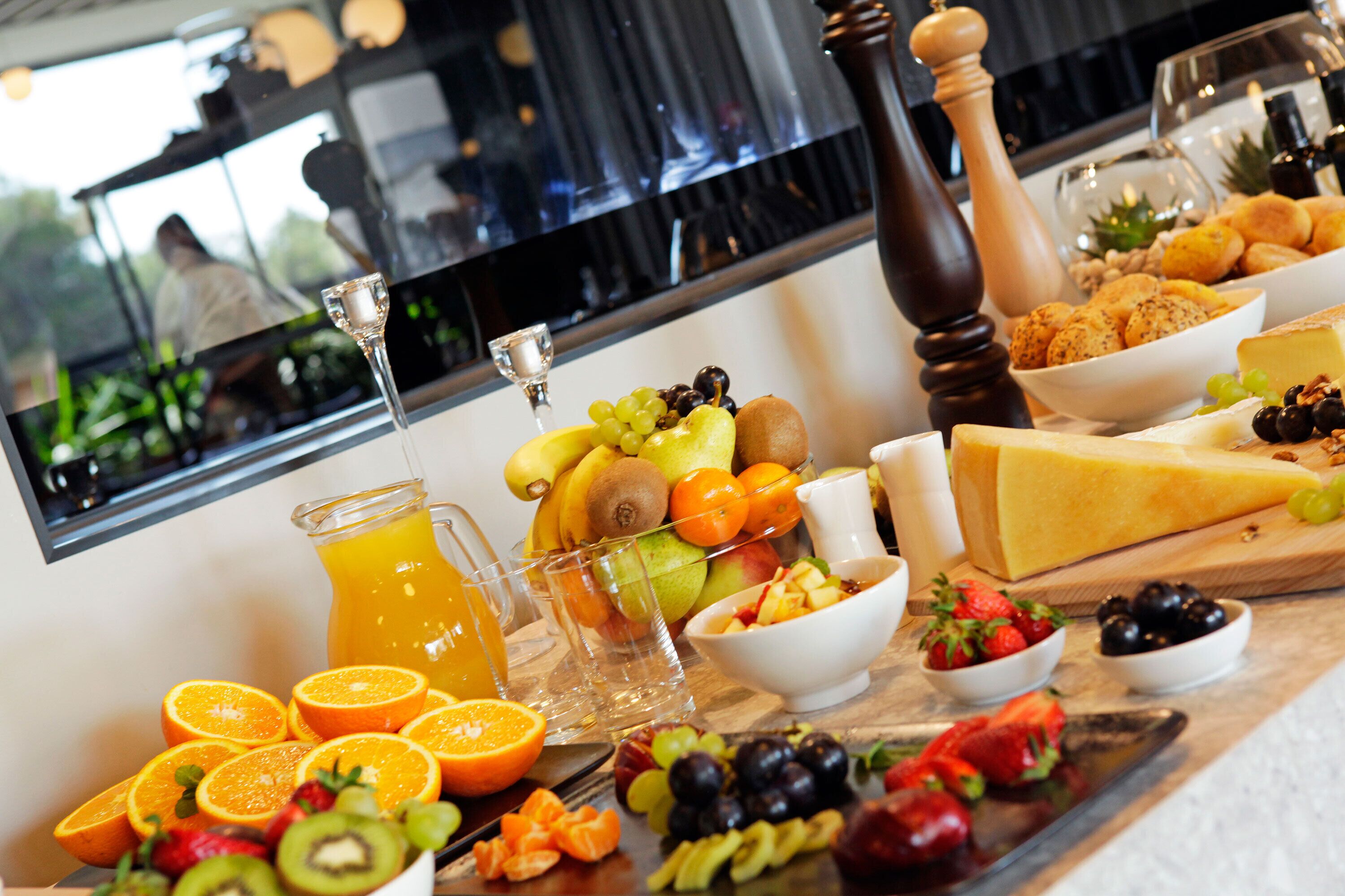 Un bufé de desayuno con frutas, queso y pan.