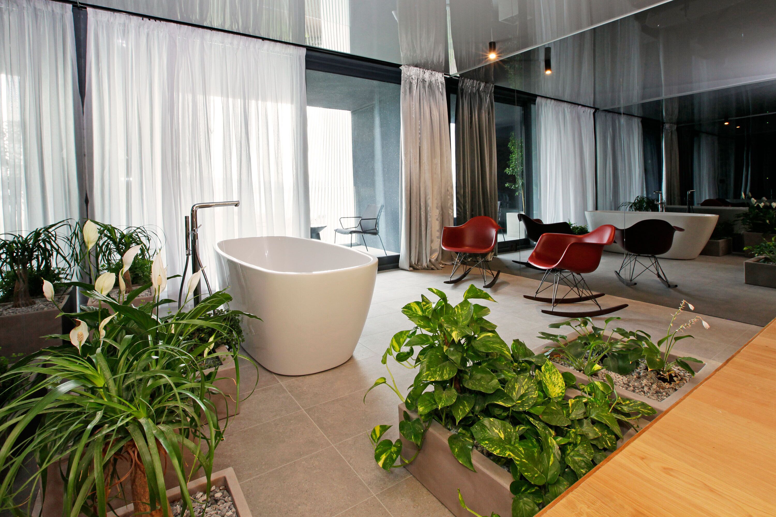 Une salle de bain moderne avec une baignoire sur pieds, deux fauteuils à bascule et des plantes en pot.