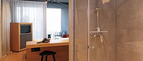 Ein modernes Badezimmer mit einer gläsernen Duschkabine, einem Holztisch mit Telefon und einem Barhocker.