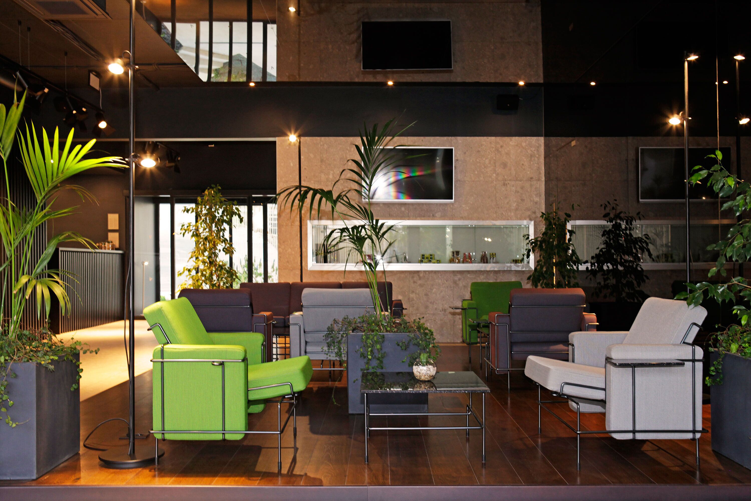 Un espacio lounge moderno con asientos, plantas y una barra.