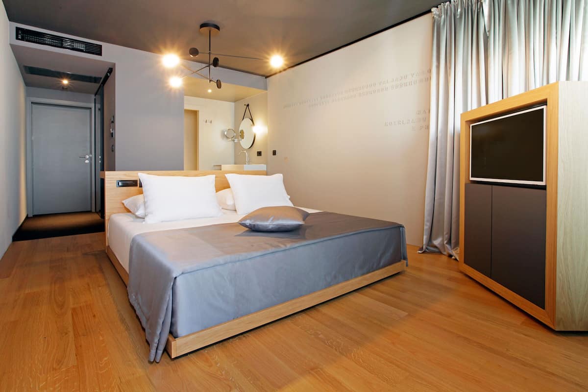 A modern bedroom with a bed, a wardrobe, and a mirror.