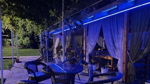 Un patio al aire libre con mobiliario de mimbre y una zona de estar cubierta.