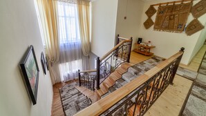 Una escalera con barandillas de madera y un tapete estampado.