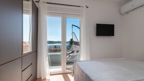 A bedroom with a bed, a television, a sliding glass door, and a view of a bridge. - Villa Eight by A (Okrug)
