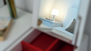 A miniature model of a hotel room with a bed, nightstand, lamp, and a red interior. - Villa Eight by A (Okrug)