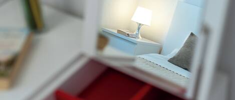 Een miniatuurmodel van een hotelkamer met een bed, nachtkastje, lamp en een rode inrichting.