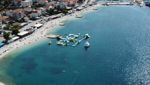 An aerial view of a coastal town with a marina, sandy beach, and residential buildings. - Villa Eight by A (Okrug)