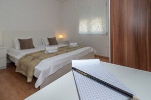 A bedroom with a bed, a bedside table with a lamp, and a window with a patterned curtain. - Villa Eight by A (Okrug)